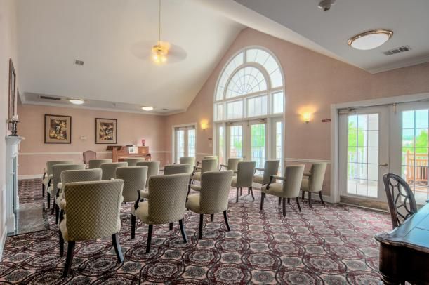 A well-lit conference room featuring numerous chairs arranged for a meeting, with large windows allowing natural light to fill the space.