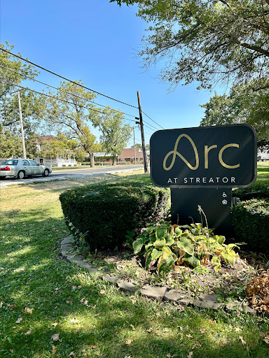 The Arc sign located in a landscaped area, surrounded by trees and greenery.