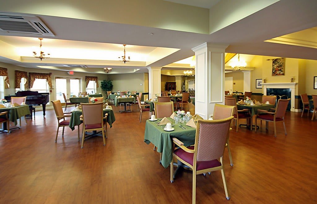 A spacious dining area with neatly arranged tables and chairs on a wooden floor.