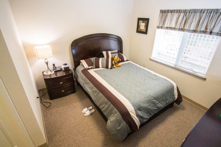 A cozy bedroom with a neatly made bed, nightstand, and lamp.