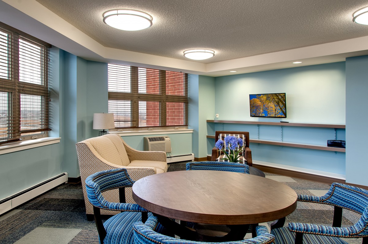 A cozy living room with modern furniture, including a round table surrounded by chairs and an armchair by the window.