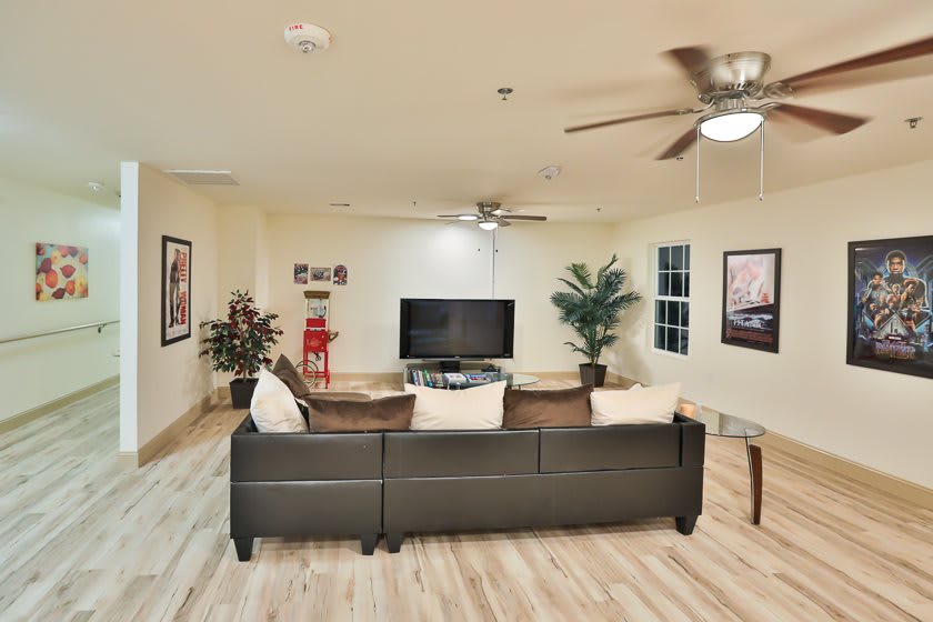 A modern living room with a large sofa, TV, and ceiling fans.