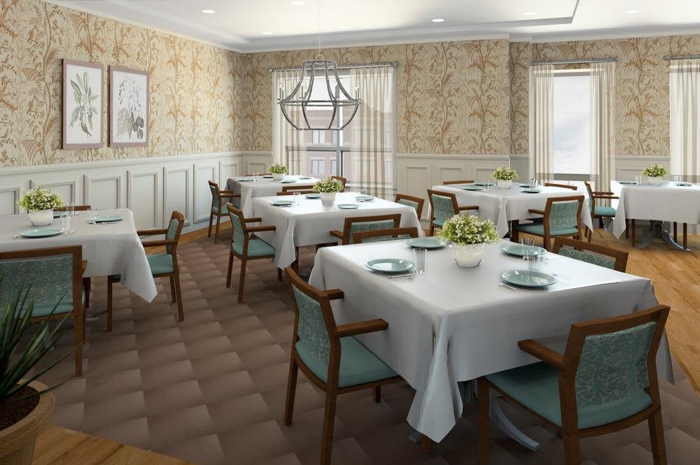 An elegant dining room with neatly arranged tables and chairs, adorned with white tablecloths and soft lighting from a central chandelier.