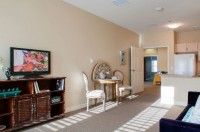 A cozy room with a small table and two chairs, adorned with floral artwork and a bookshelf.