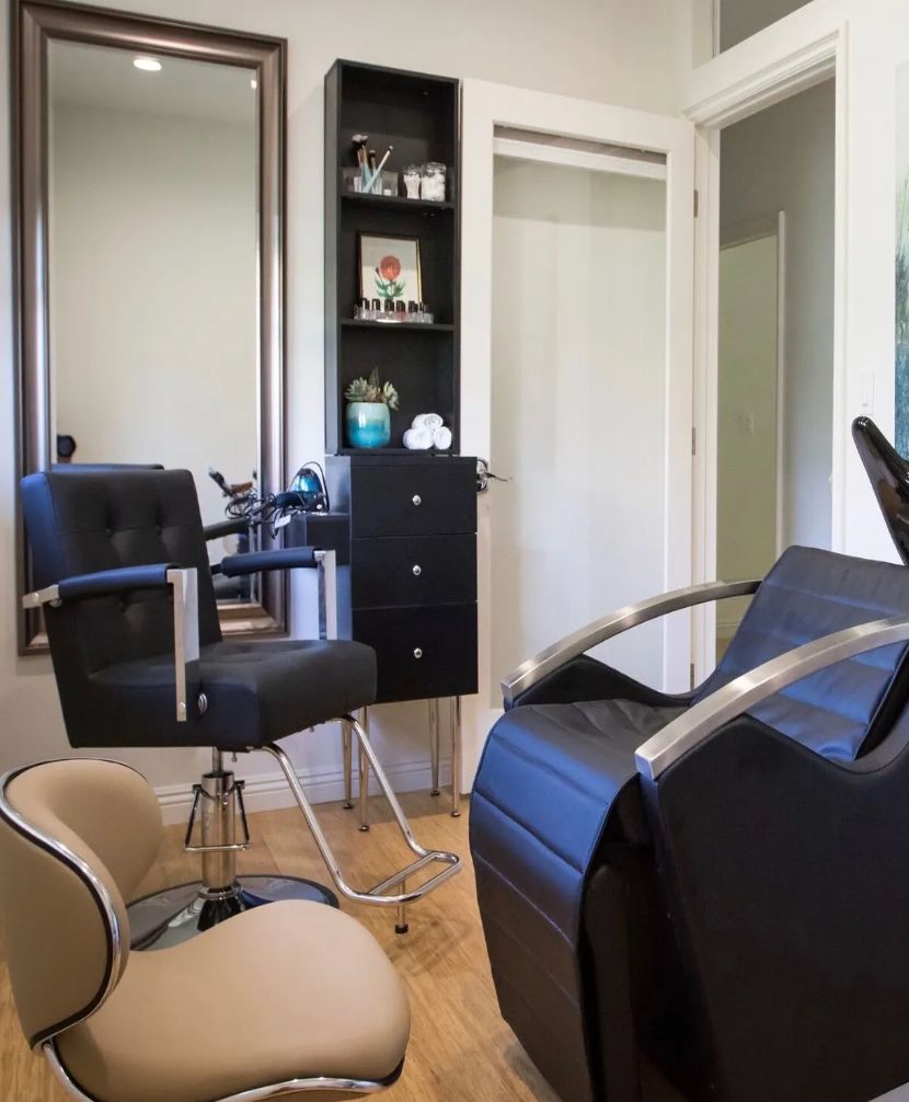 A modern hair salon with comfortable chairs and a large mirror.