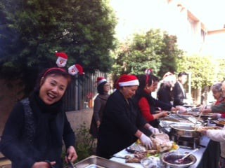 People celebrating outdoors with festive attire and cooking stations.