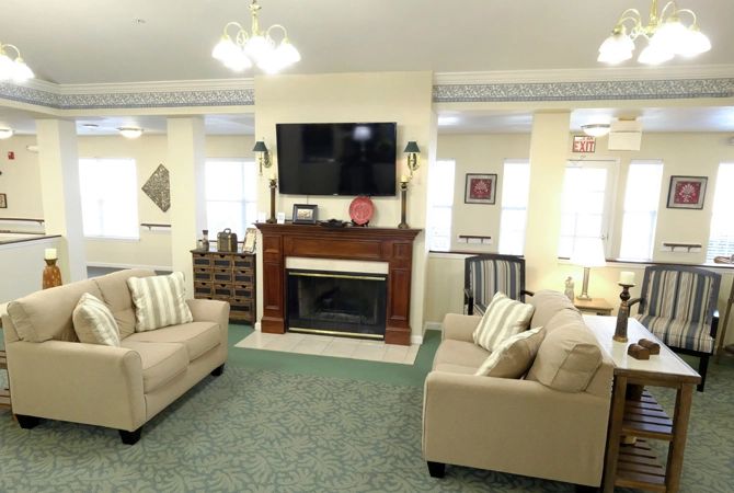 A cozy living room with two beige sofas facing a fireplace and a mounted television.