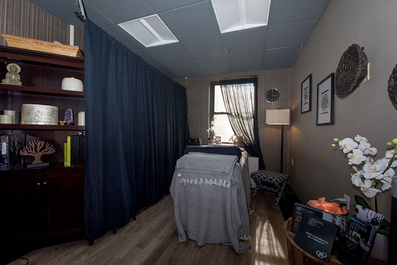 A serene massage therapy room with a comfortable bed, soft lighting, and cozy decor.