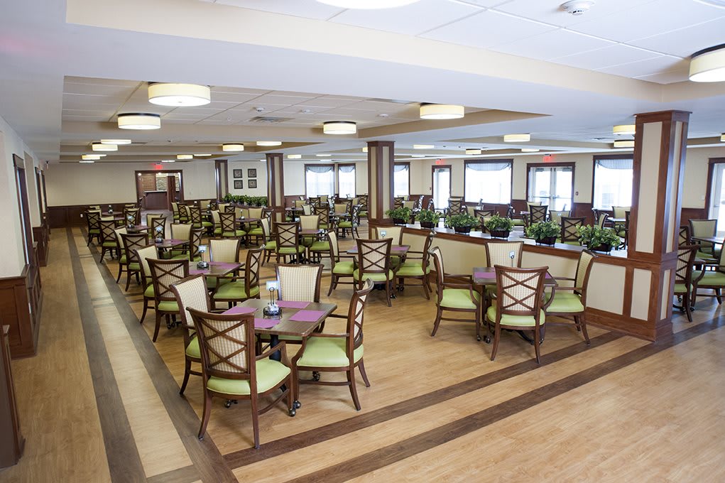 A spacious dining area with neatly arranged tables and chairs, featuring wood flooring and ample lighting.