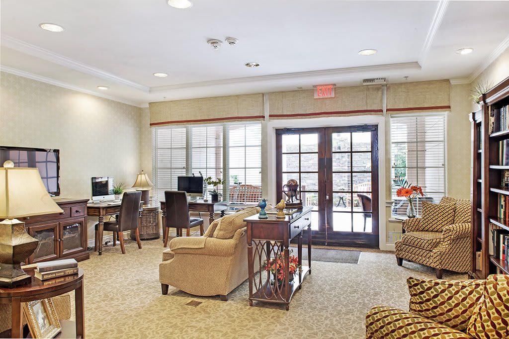 A comfortable lounge area with seating, computers, and large windows.