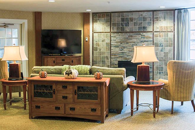 A cozy living room with a couch, wooden furniture, and a television mounted on the wall.