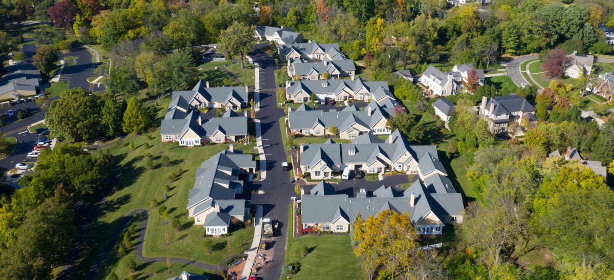 Aerial view of a suburban residential neighborhood with houses and green spaces.