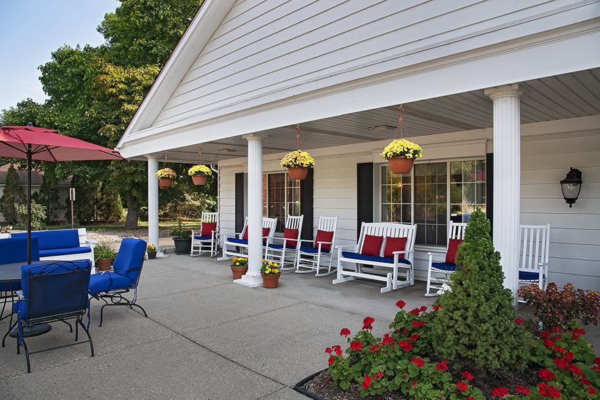 A charming porch with rocking chairs and hanging plants creates a cozy outdoor seating area.