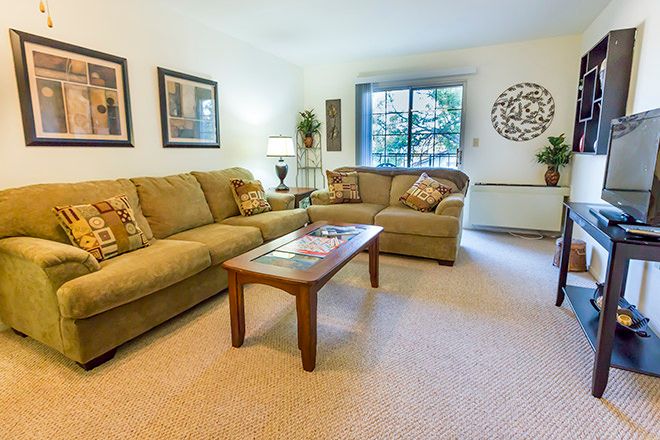 A cozy living room with comfortable sofas and a coffee table, decorated with artwork and a large window providing natural light.