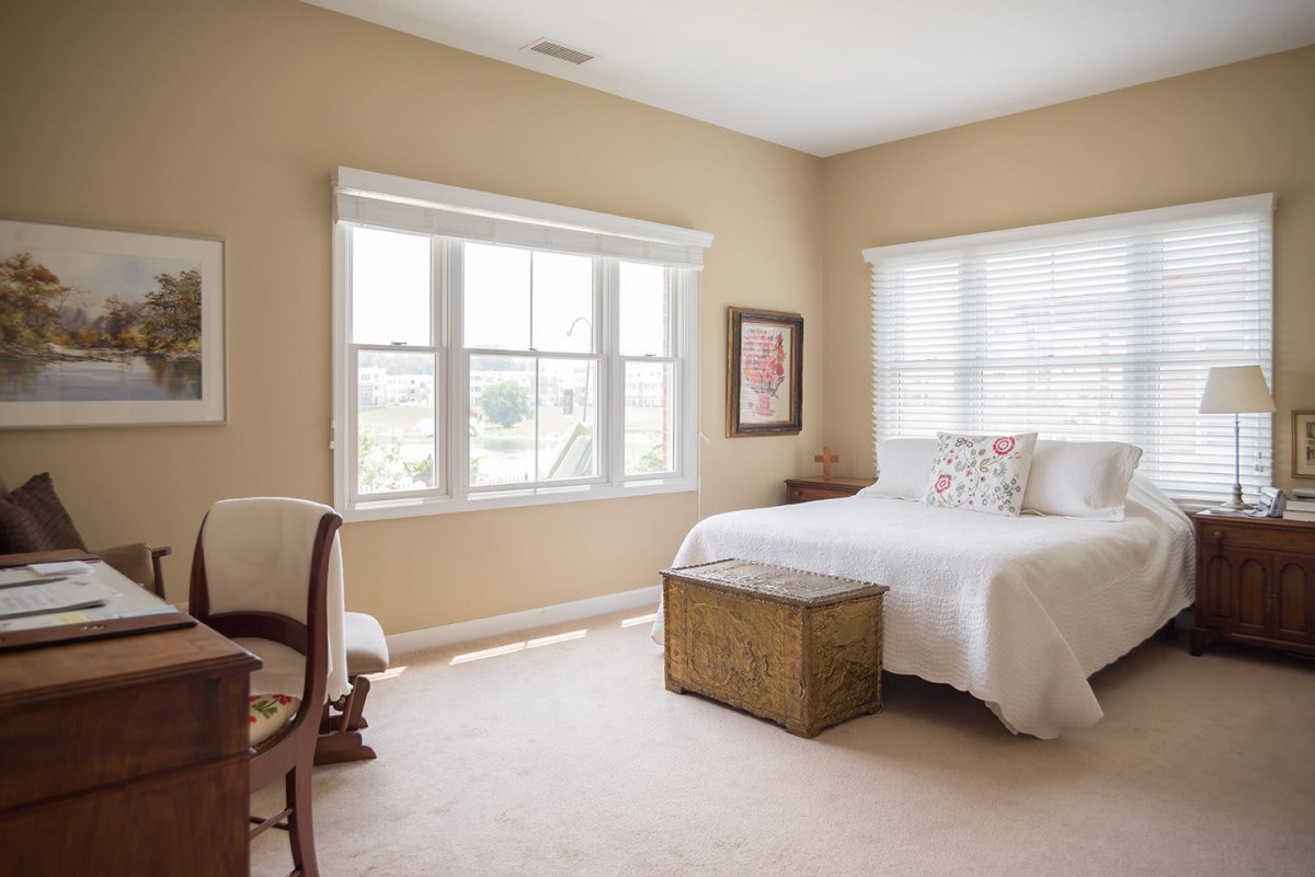 A bright and cozy bedroom with minimalist decor, featuring a bed, windows, and neutral tones.