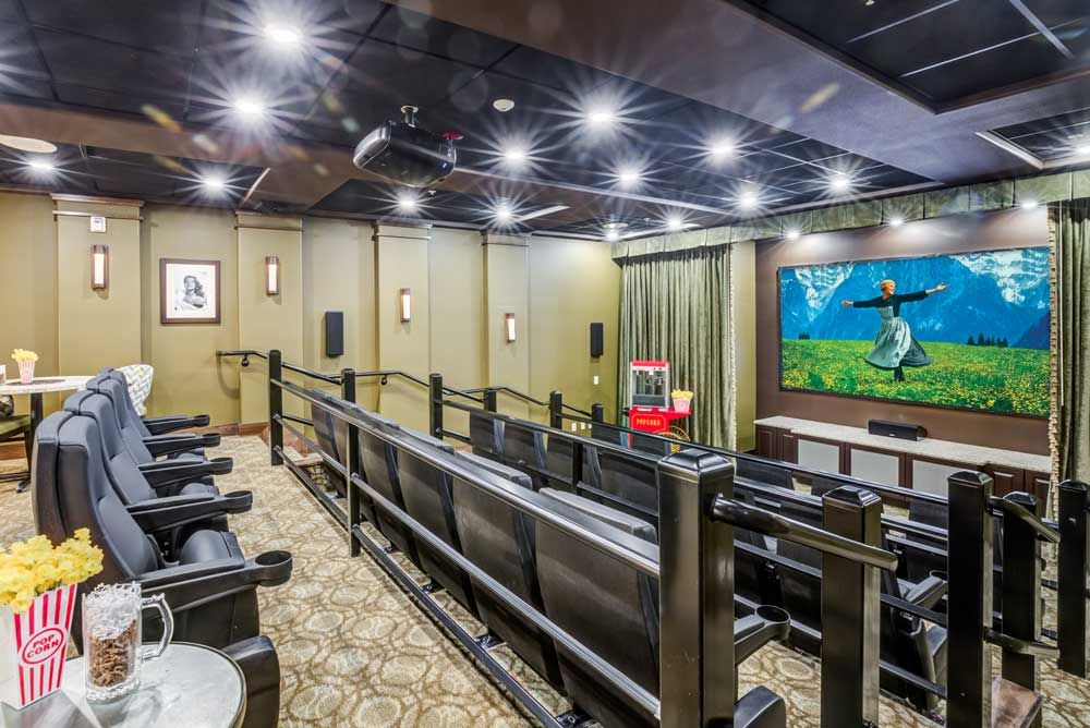 A well-equipped home theater room with tiered seating and a large screen.