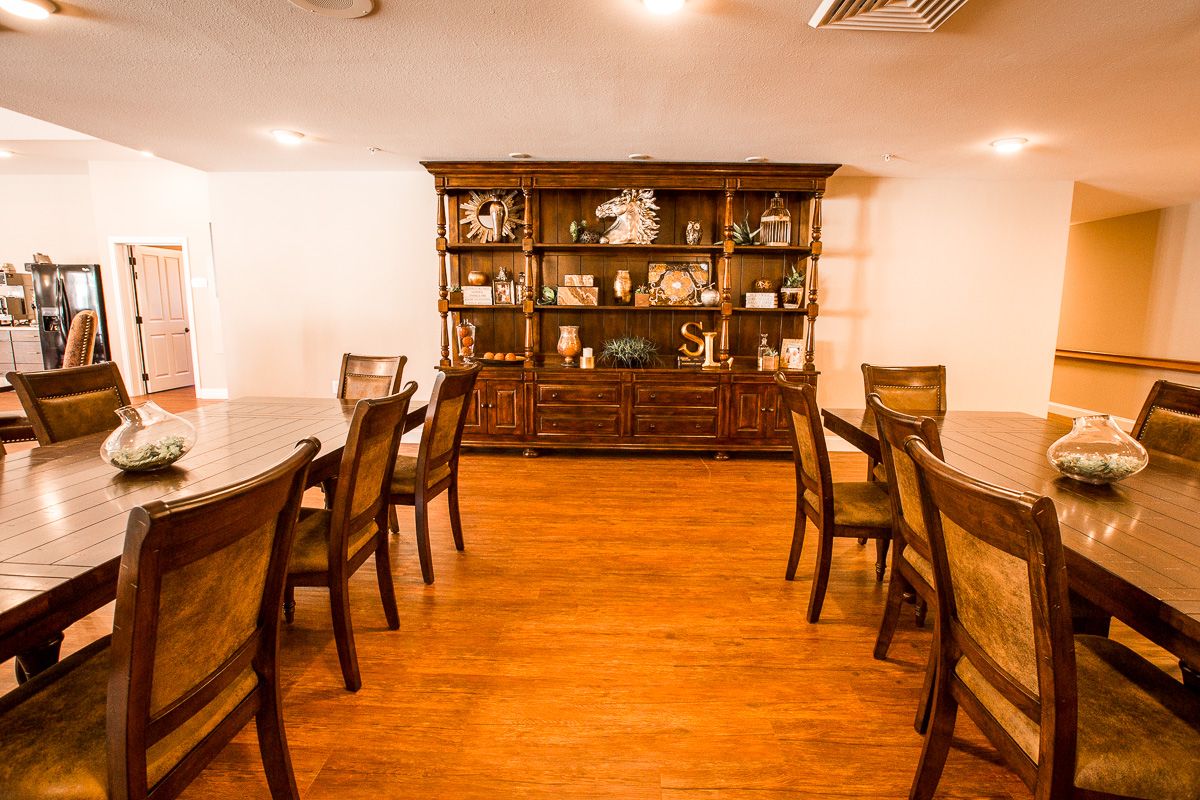 A dining room with a long table, chairs, and a wooden cabinet against the wall.