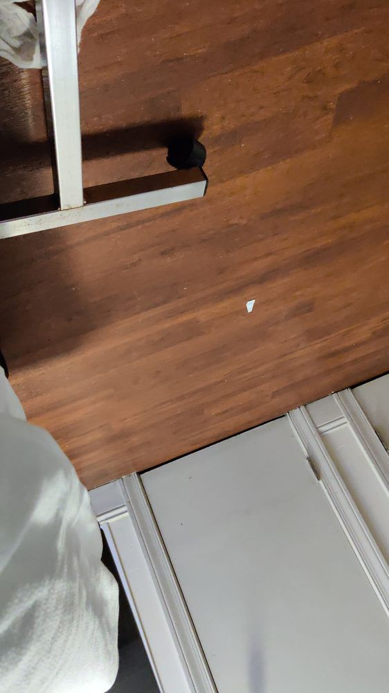 A piece of gum on a wooden floor indoors.