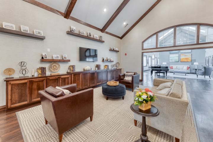 A cozy living room with high ceilings and wooden furniture, featuring a seating area and decorative shelves.