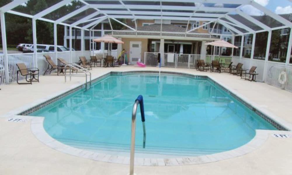 An enclosed outdoor swimming pool with patio furniture surrounding it.