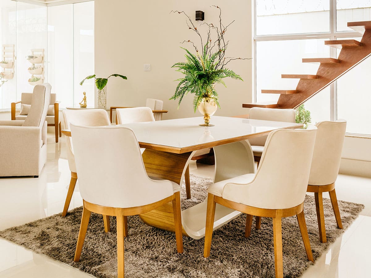 A modern dining area with a stylish wooden table, white chairs, and a decorative indoor plant centerpiece.