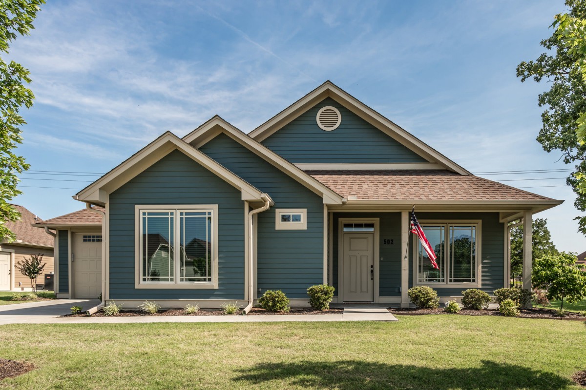 A single-story suburban house with blue siding and a well-maintained front lawn.