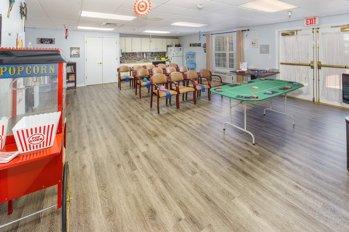 A spacious community room with chairs, tables, and games set up for activities.