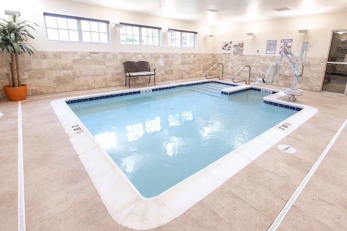An indoor swimming pool with tiled edges and a seating area.