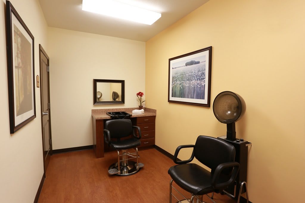 A cozy hair salon room with a styling chair, mirror, and a hair dryer station.