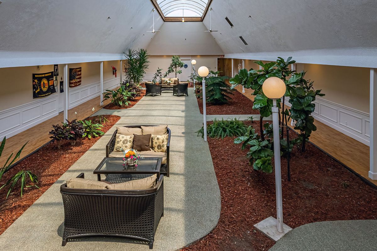 A modern indoor atrium with a skylight, featuring lush plants and a comfortable seating area.