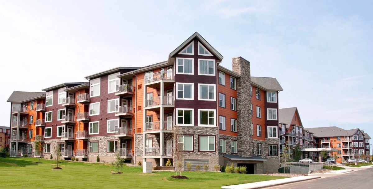 A modern multi-story apartment building with a blend of brick and stone facade.