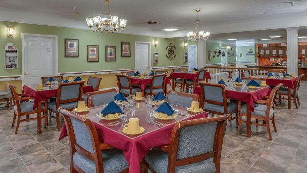 An elegantly set dining room with neatly arranged tables and chandeliers.