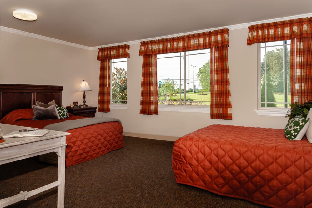 A cozy hotel room with twin beds, adorned with orange bedding and matching curtains.