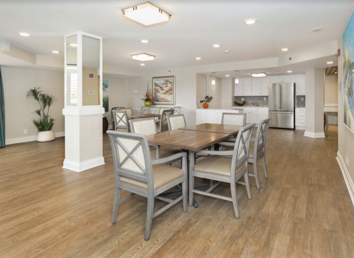 A modern dining area with a wooden table and chairs, adjacent to a sleek kitchen.