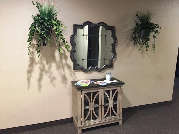 A decorative console table with a mirror and wall-mounted plants.