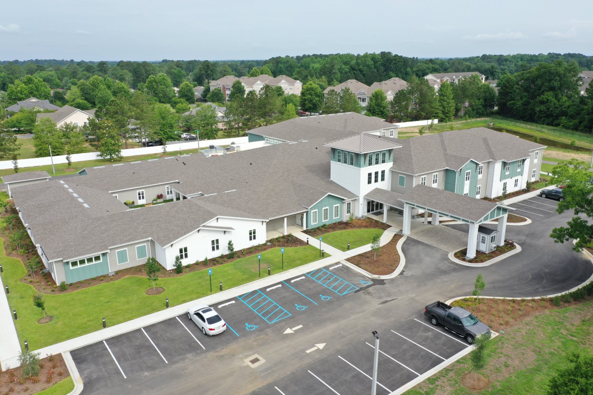 Aerial view of a large building with a parking lot and surrounding greenery.