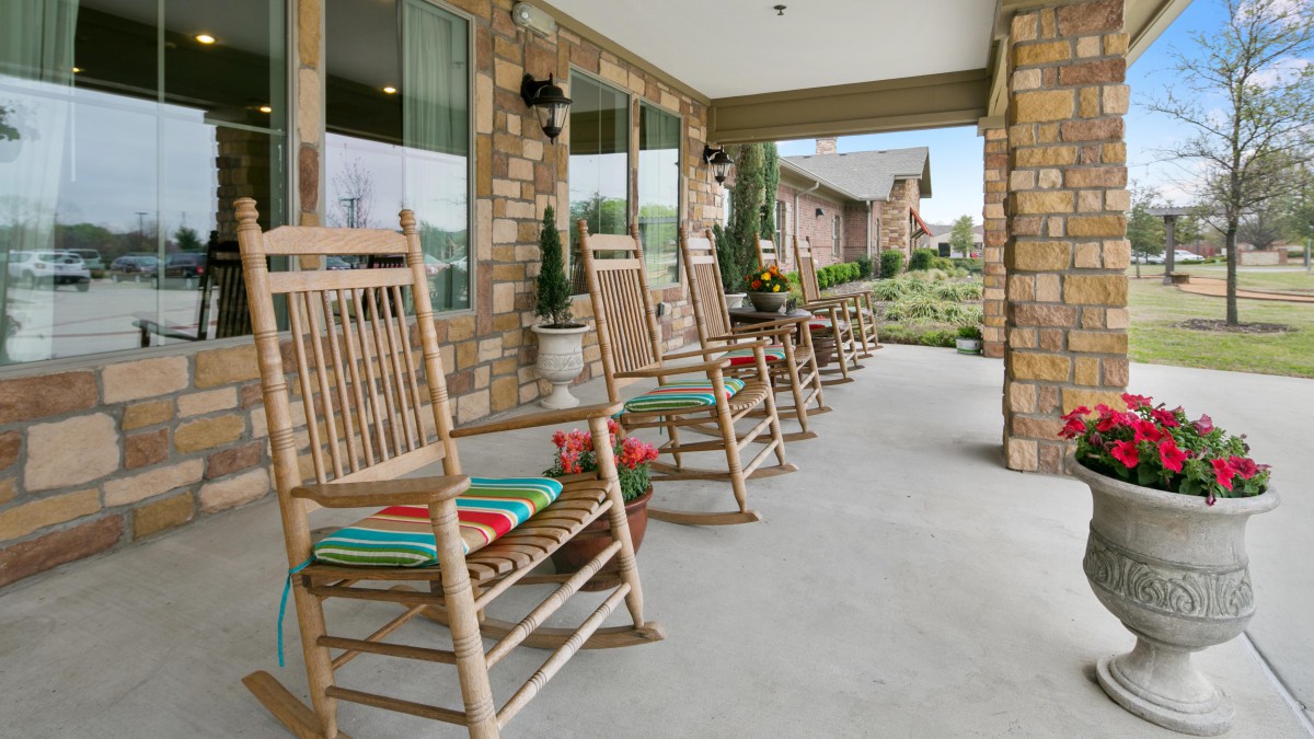 A row of wooden rocking chairs on a cozy porch, offering a relaxing outdoor seating area.