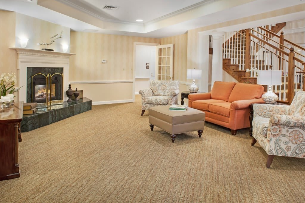 A cozy living room with a fireplace, carpeted floor, and comfortable seating.