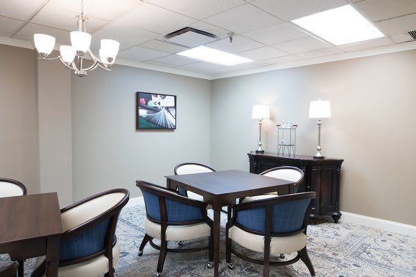 A well-lit meeting room with a conference table surrounded by four chairs, decorated with modern artwork and ambient lighting.