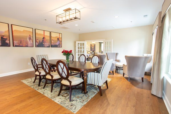 A modern dining room with a large wooden table, elegant chairs, and stylish artwork on the wall.