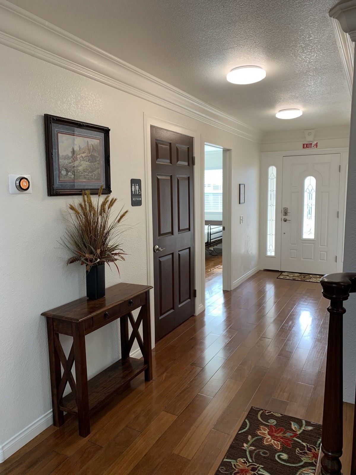 A well-lit hallway with a wooden console table, picture frame, and doors leading to other rooms.