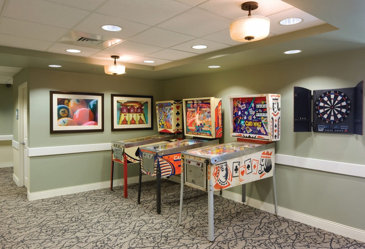 A cozy games room featuring several vintage pinball machines.