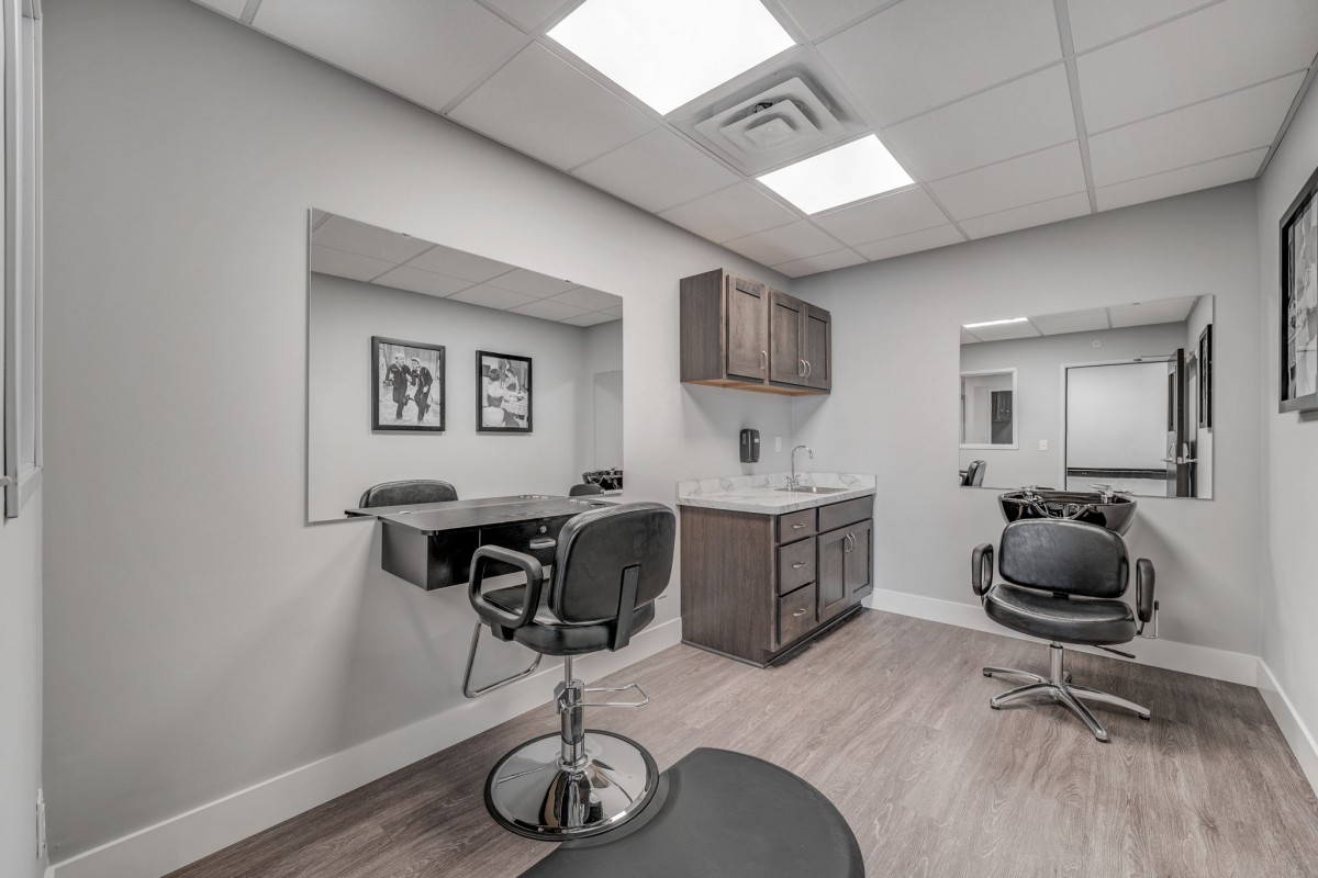 A modern hair salon interior with chairs, mirrors, and cabinets.