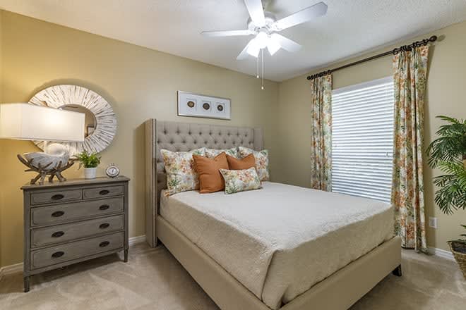 A cozy and well-decorated bedroom with a tufted headboard, stylish pillows, and a mirror above the dresser.