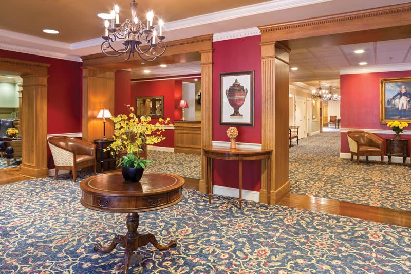 Elegant hotel lobby featuring a chandelier, wood paneling, and a table with flowers.