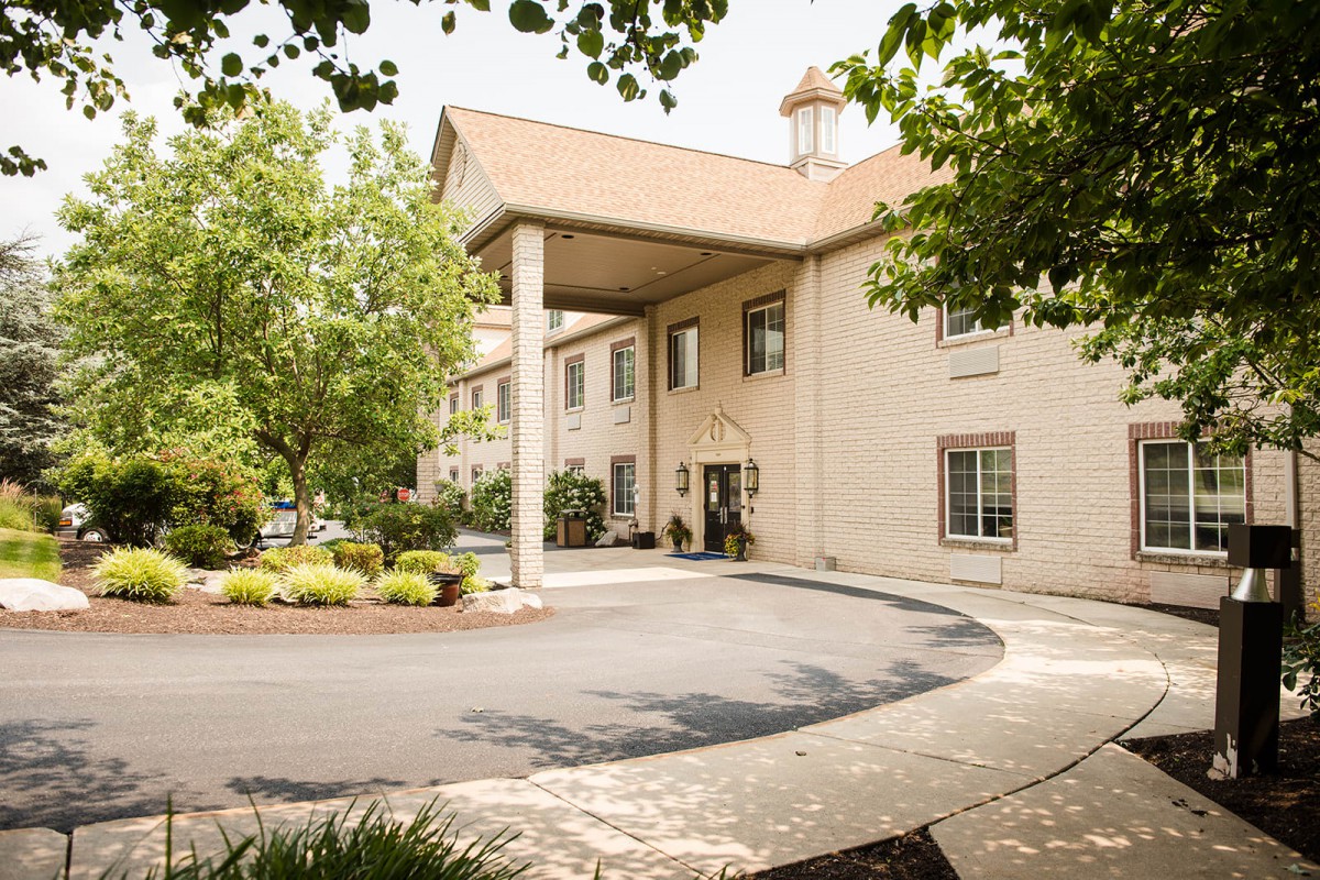 The exterior of a welcoming hotel entrance surrounded by lush greenery.