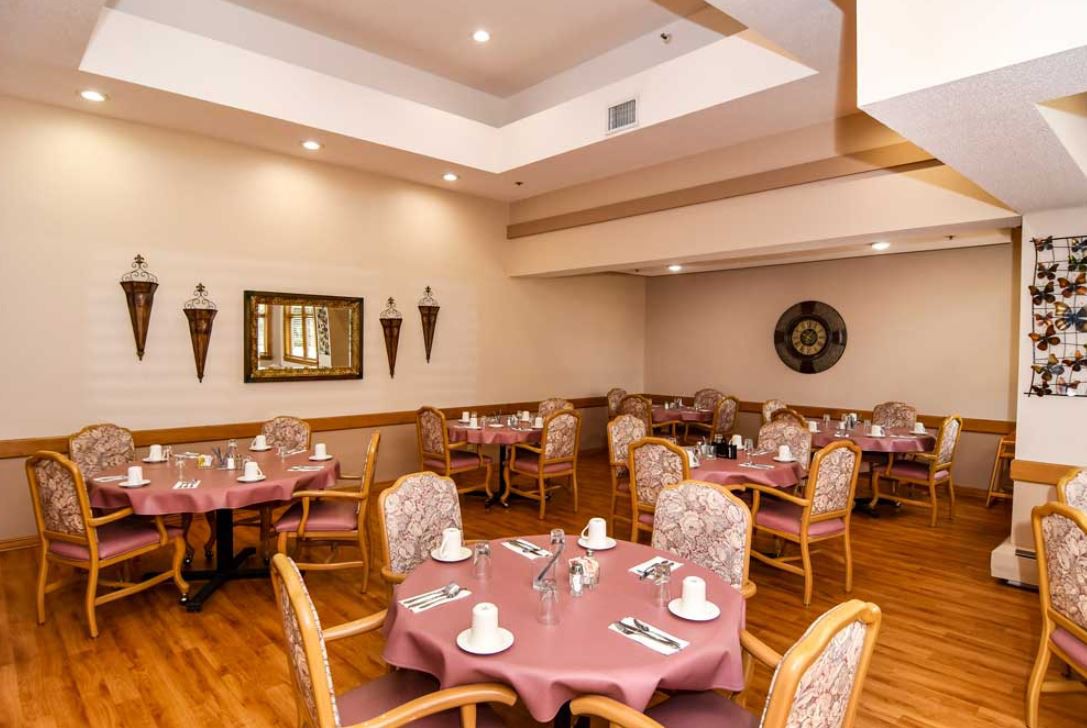 An empty restaurant dining room with neatly arranged tables and chairs, ready for guests.