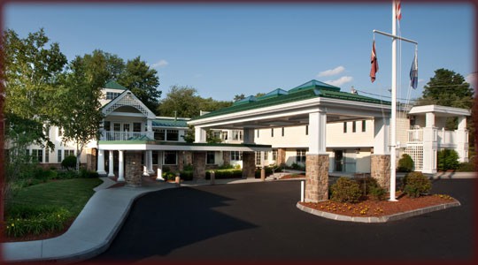 The image shows the entrance of a hotel with a covered driveway and modern architectural design.