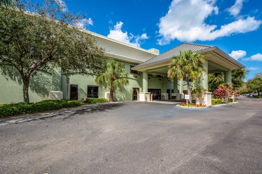 A hotel entrance with palm trees and a clear blue sky.