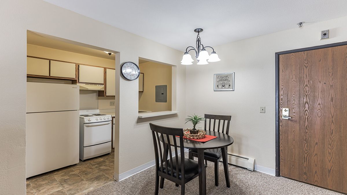 A cozy dining area with a small round table and two chairs, adjacent to a compact kitchen.
